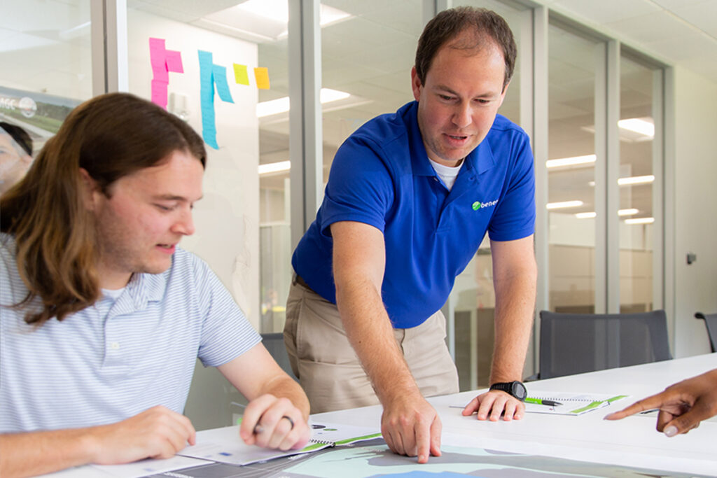 photo of Benesch team members reviewing a project plan and discussing various ways to construction the project, in a Benesch office