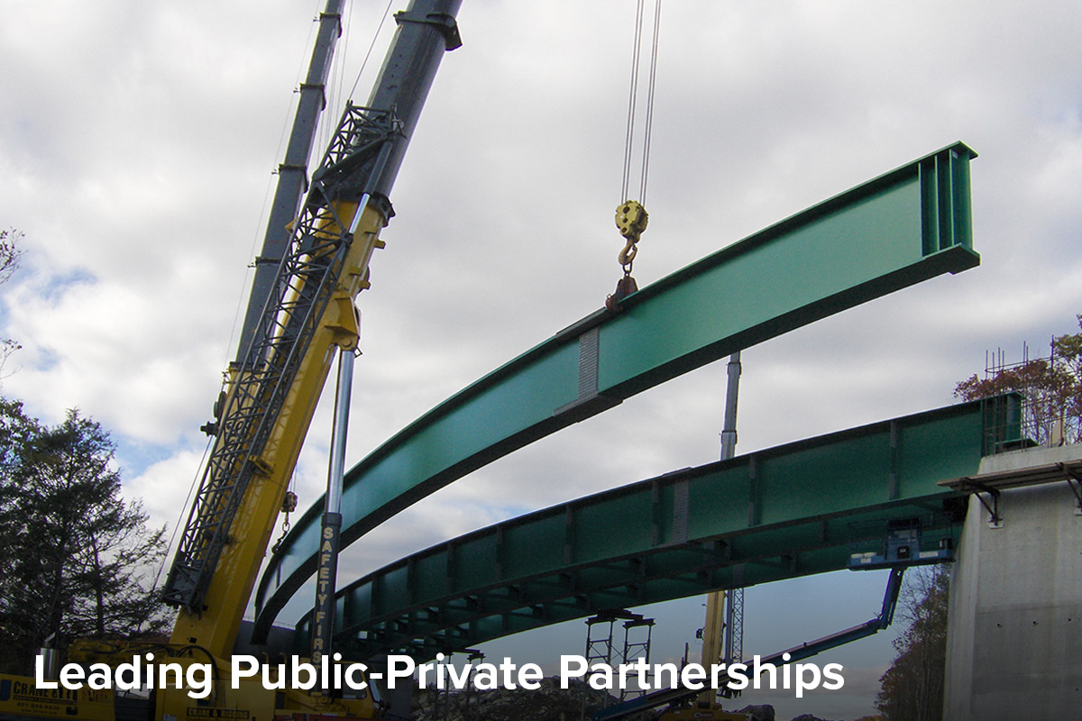 photo of curved girders being placed by a crane for a new highway overpass