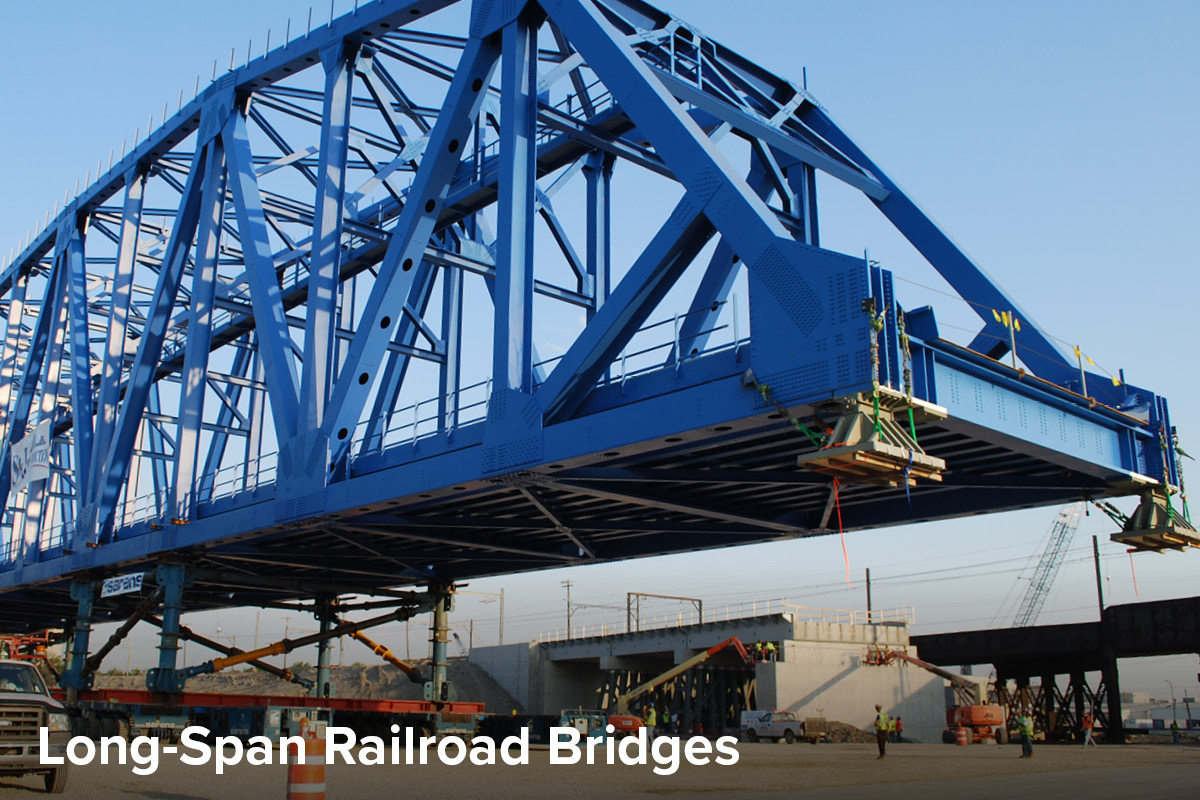 image of 400-foot blue truss railroad bridge loaded onto a self propelled modular transporter, waiting to be slid into its permanent position