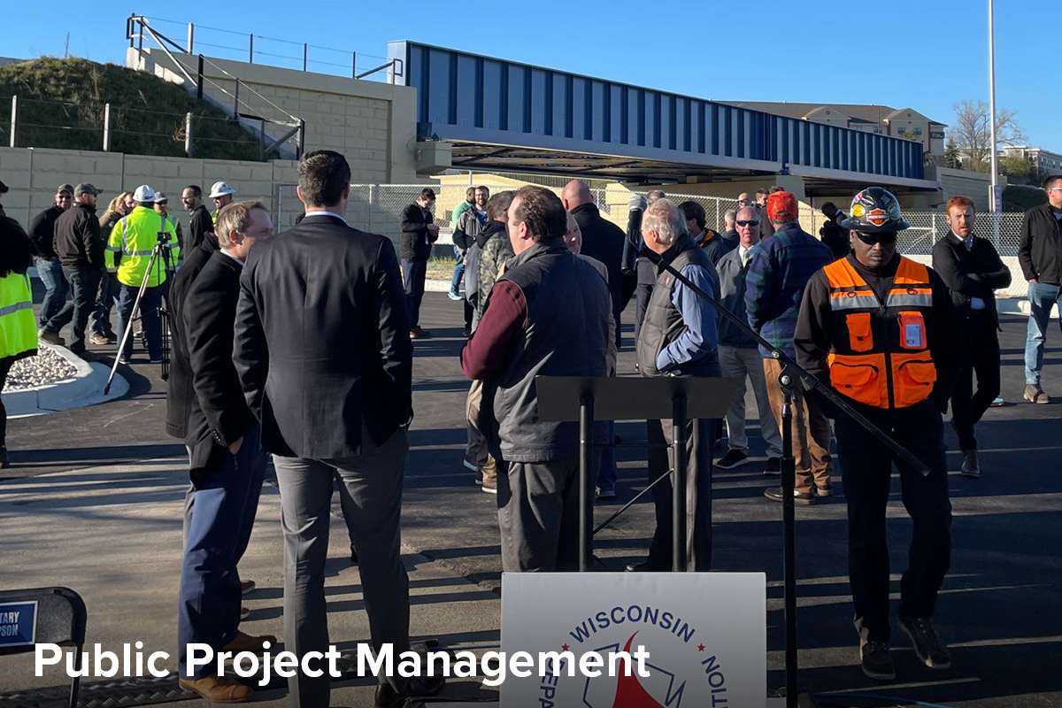 view of a crowd at the ribbon cutting for a new train crossing over an highway interchange in Milwaukee