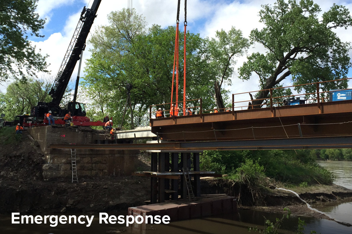 View of a new bridge being put in place over a waterway following torrential rain which washed away the original structure