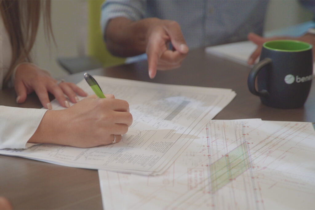 close up image of two people reviewing a set of plans for a bridge, creating mark ups for review\