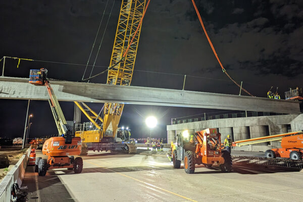 A photo of a crane placing beam in bridge for E-470