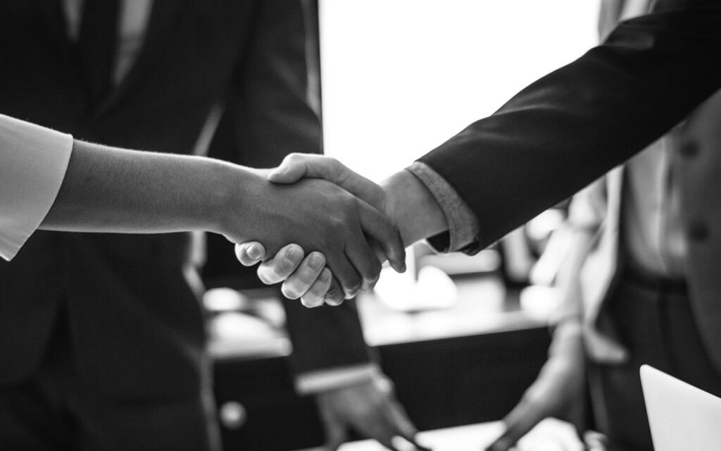 Photo of a handshake in a corporate room