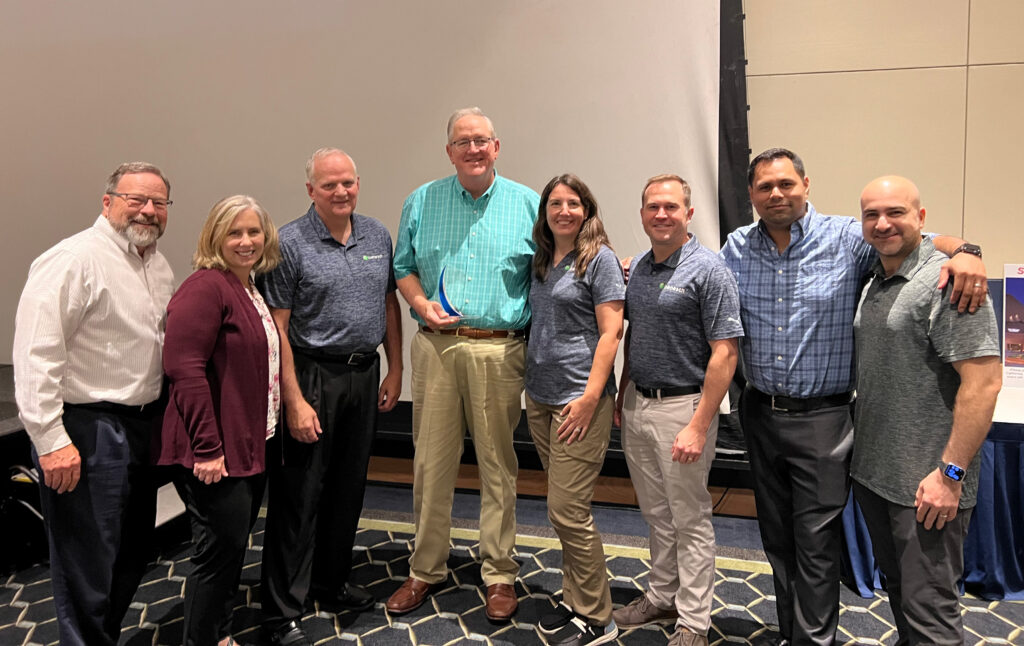 A photo of group of Benesch employees and Rick Campbell holding an award