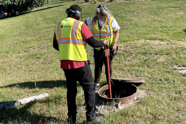 image of two Benesch water inspectors performing a leak detection at an open manhole in Romulus, MI.