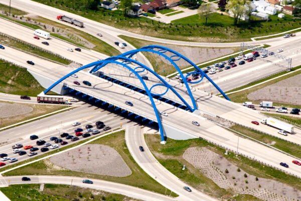 aerial view of Telegraph Road Bridge, which is a blue arch bridge with football shaped ribs, as it was designed and built to honor the Super Bowl in Detroit