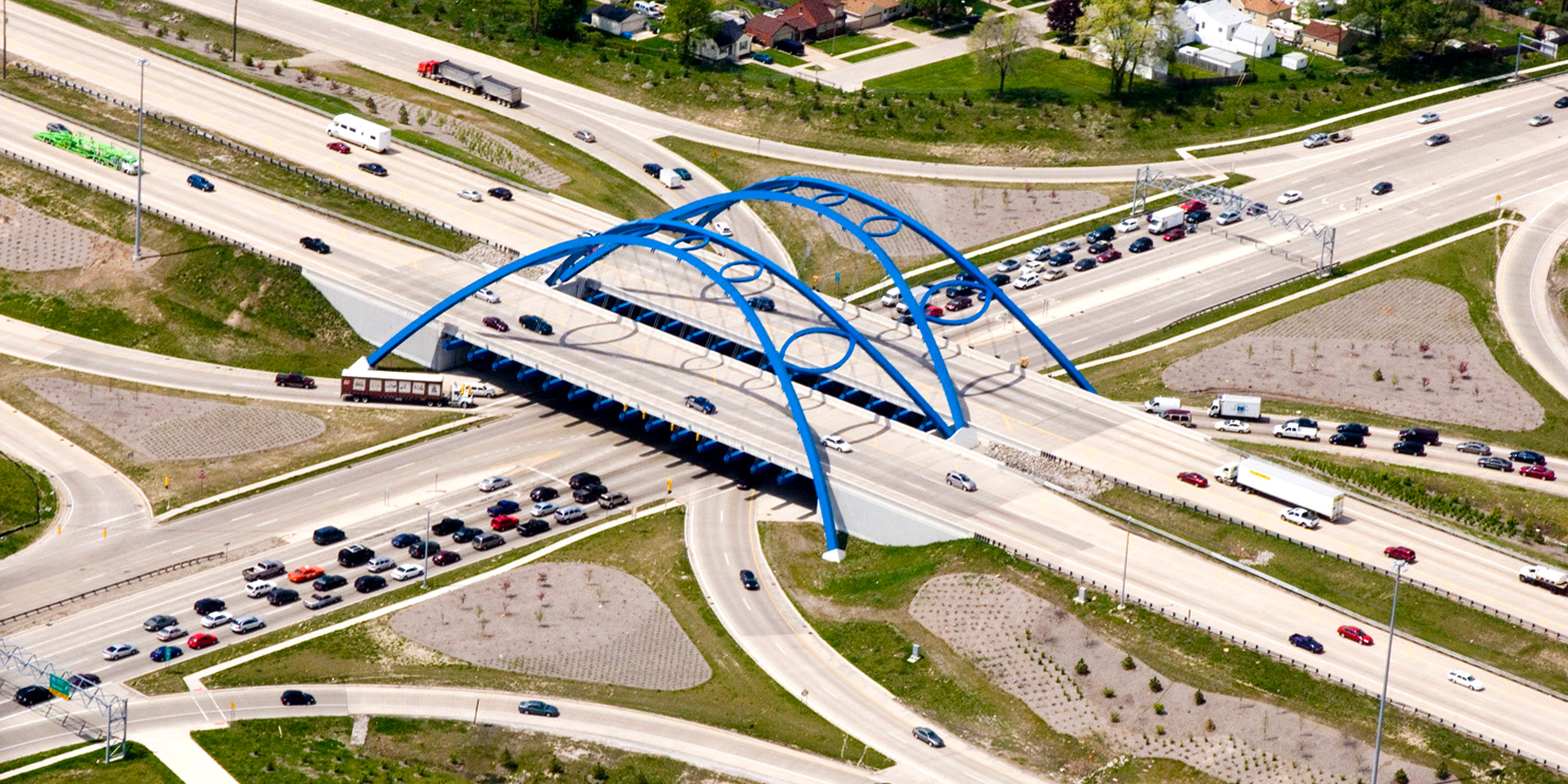 aerial view of Telegraph Road Bridge, which is a blue arch bridge with football shaped ribs, as it was designed and built to honor the Super Bowl in Detroit