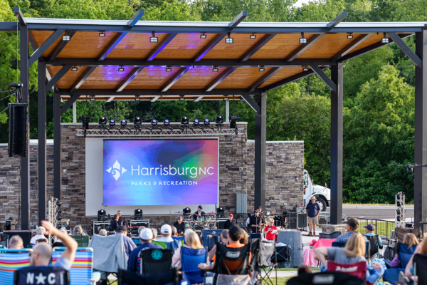 shelter at a park with a band playing and people in lawn chairs watching