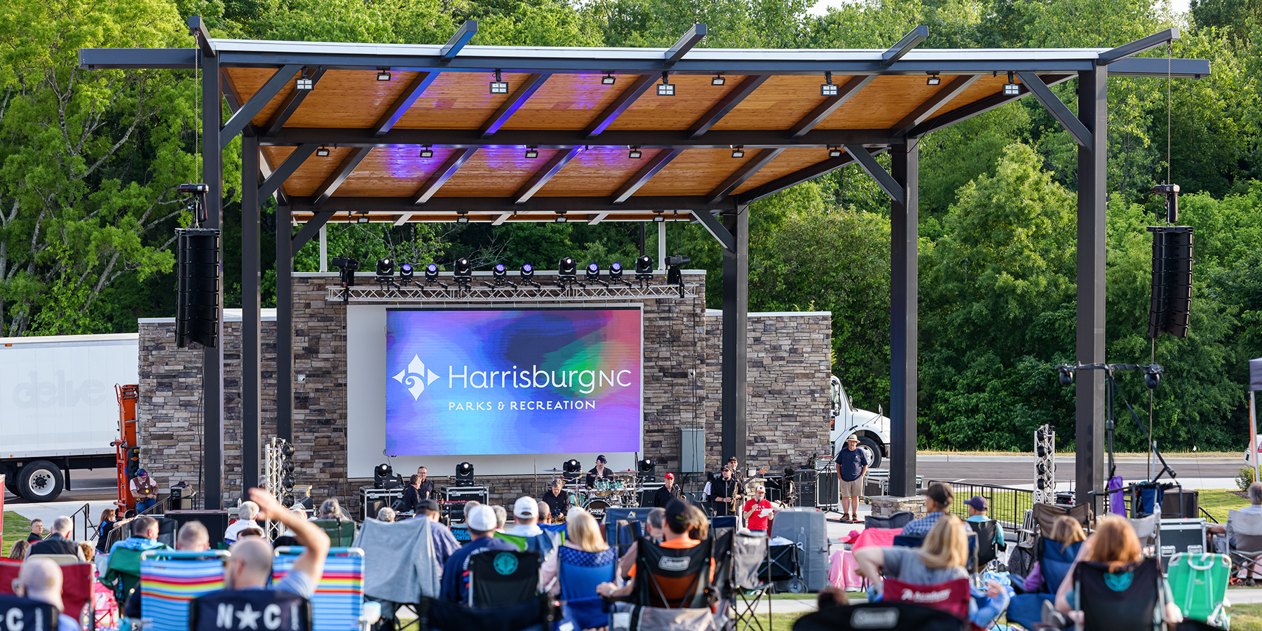 shelter at a park with a band playing and people in lawn chairs watching