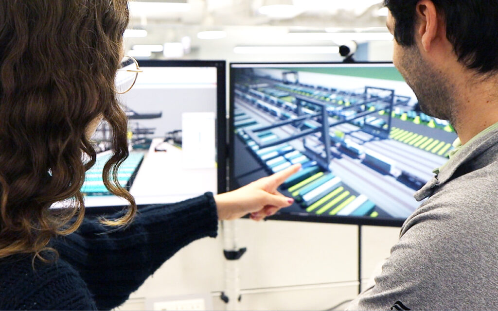 Two Benesch employees looking at a 3D model of a railroad yard in OpenRoads