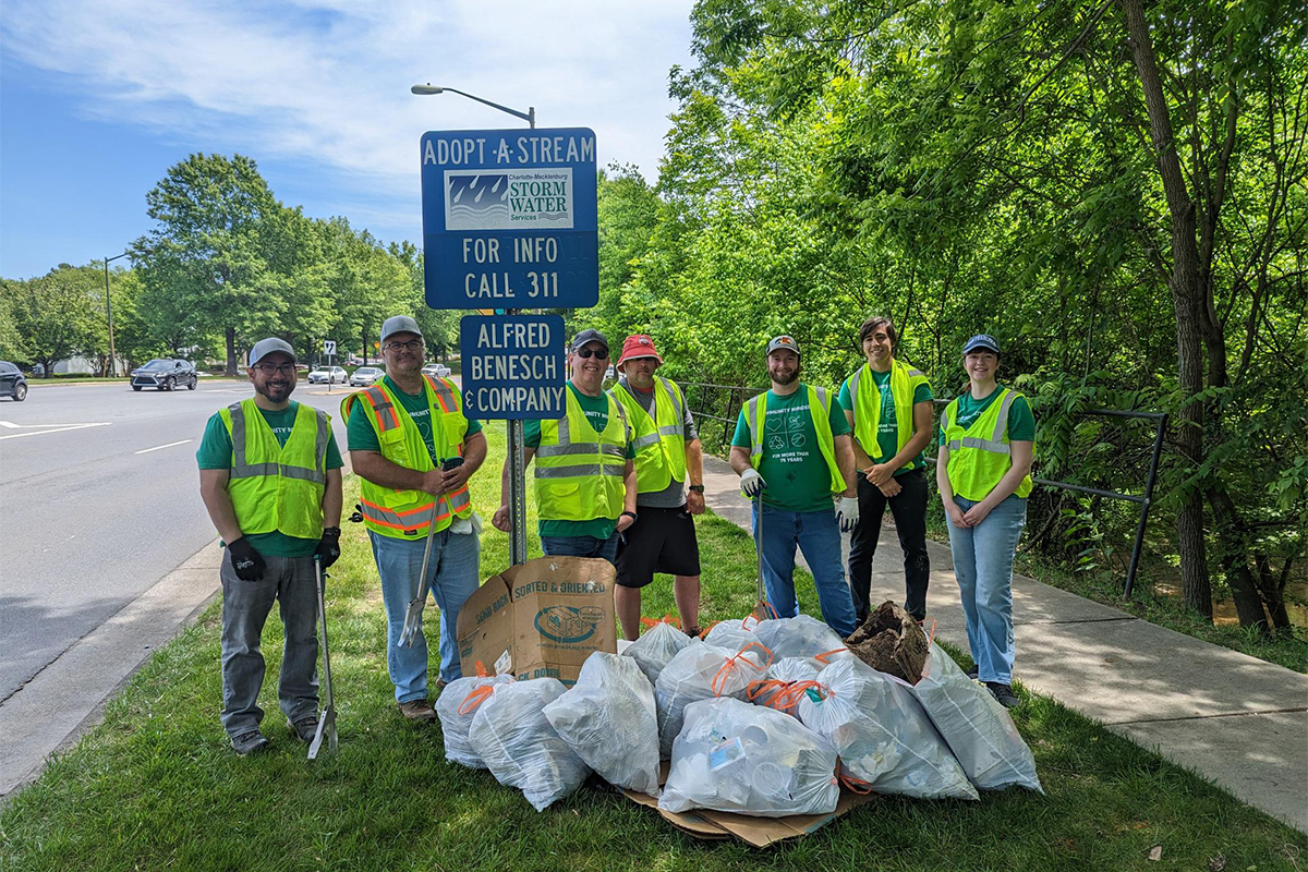 Benesch employees posing by an adopt-a-highway sign for the company after a day of trash pick-up