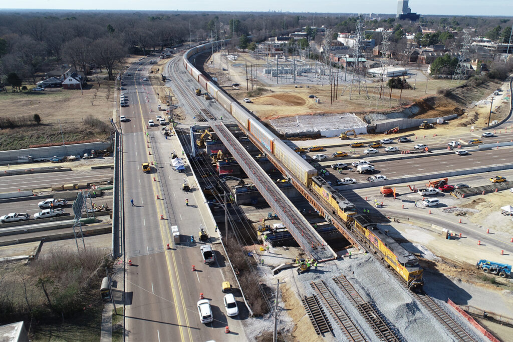 aerial view of rail bridges being constructed as a freight train passes through the construction zone