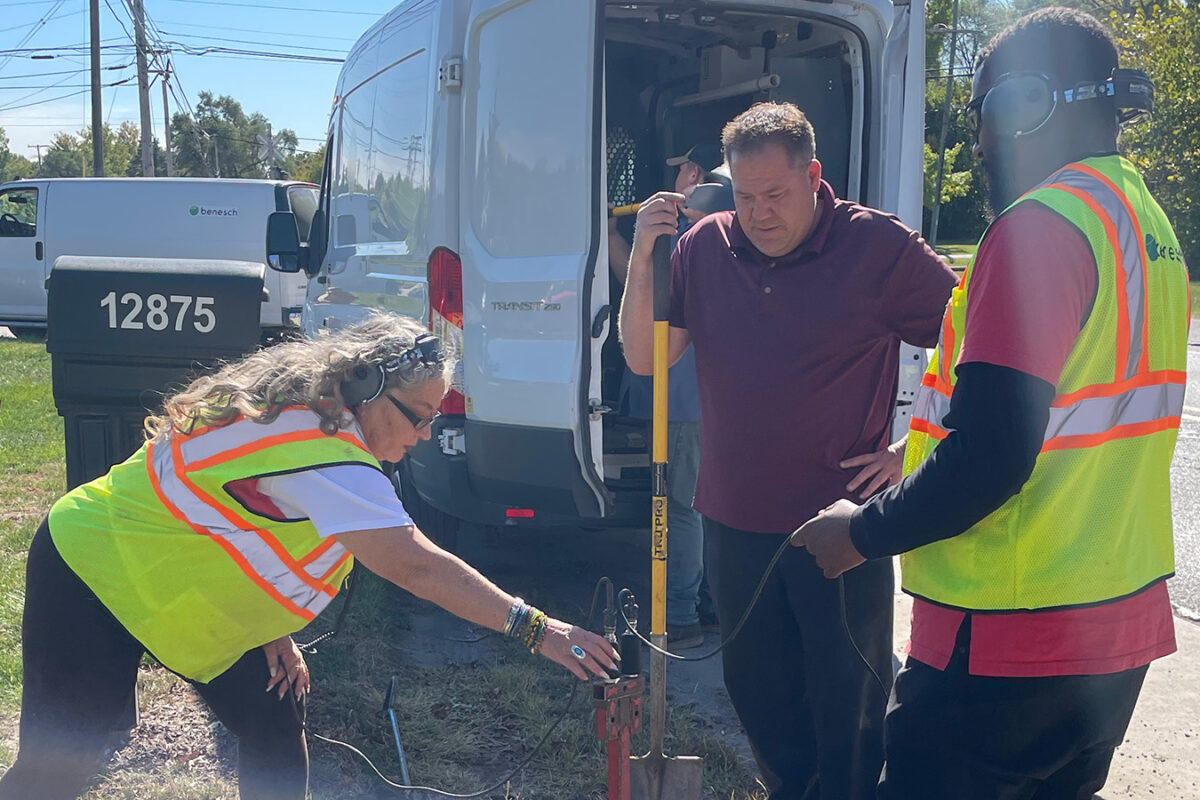 A photo of three Benesch employees in the field checking sewer for leaks with microphone