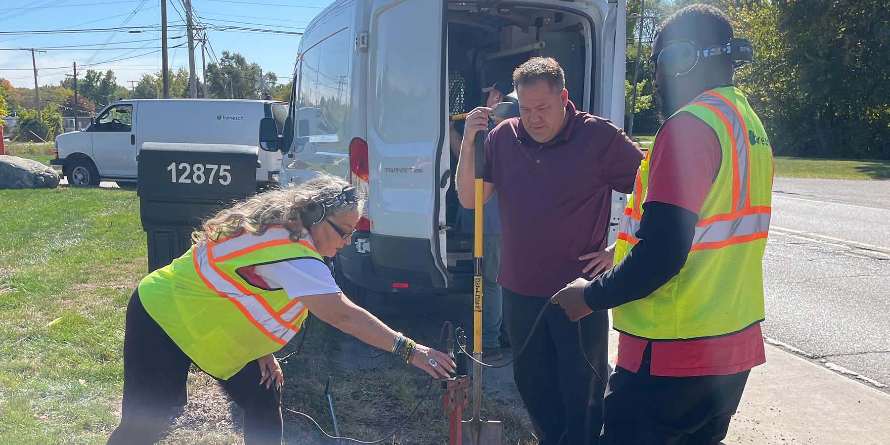 A photo of three Benesch employees in the field checking sewer for leaks with microphone