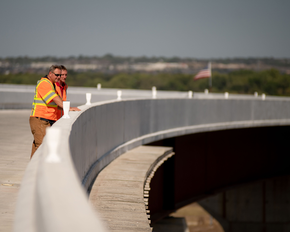 A photo of a highway bridge with two Benesch employees wearing orange vests