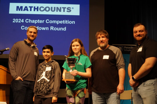 image of Benesch volunteers with winners from the MathCounts Competition day, posing with the local competition trophy