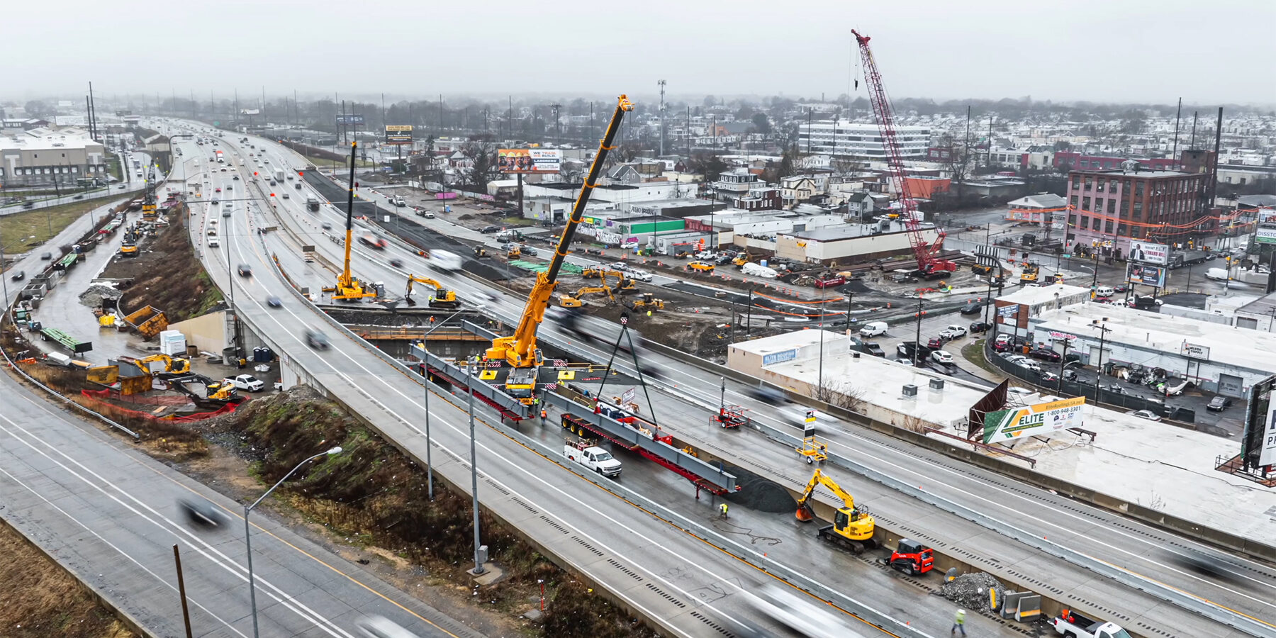 aerial view of new beams being set on I-95 as traffic continues in both directions on outside lanes, with cranes placed in middle lanes