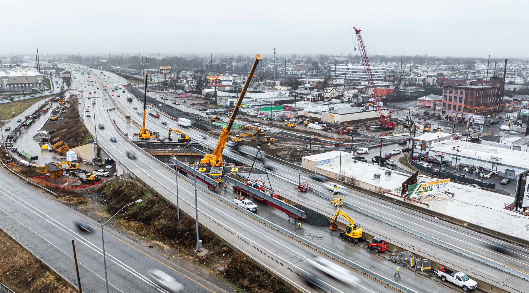 aerial view of new beams being set on I-95 as traffic continues in both directions on outside lanes, with cranes placed in middle lanes