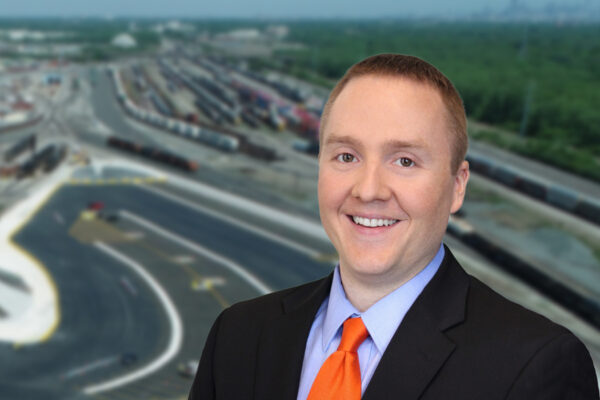 Photo of Darwin Schafer. in the background is an aerial view of the intermodal rail facility in Calumet, IL.