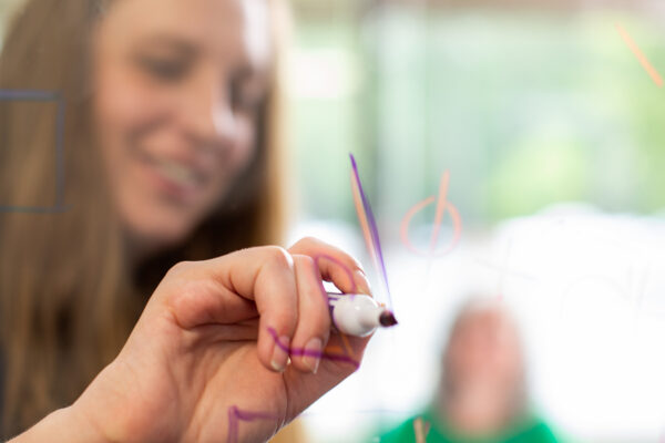 image of a Benesch employee writing with a dry erase marker in front of a room full of coworkers