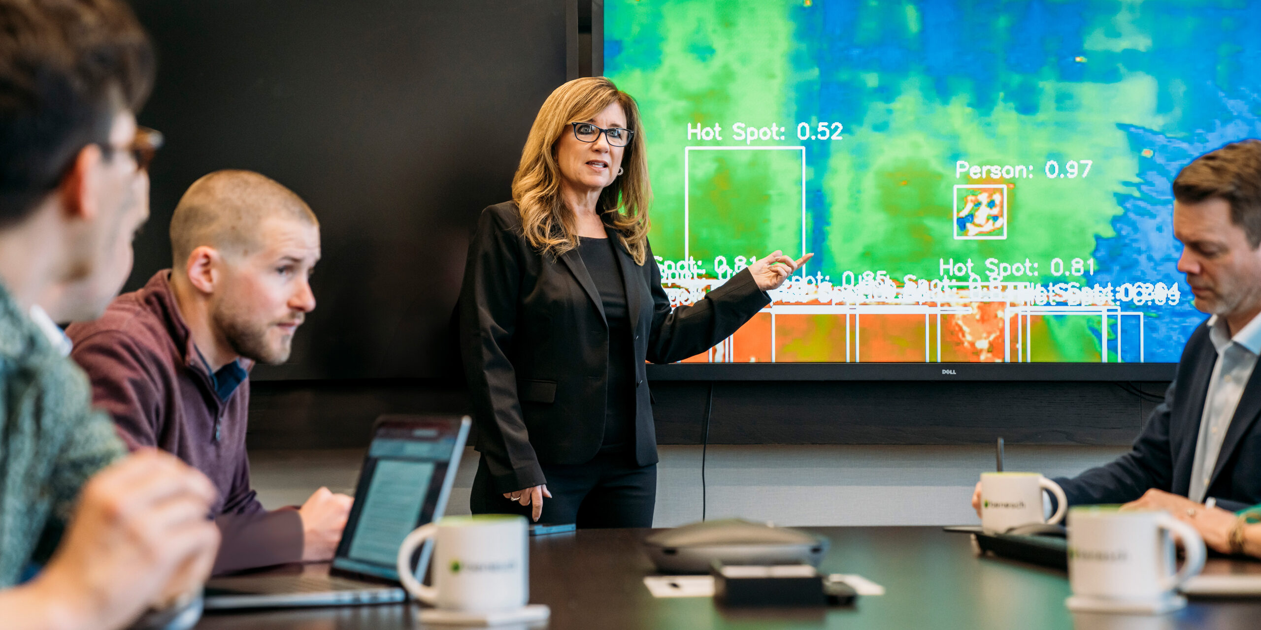 photo of Laura McGovern presenting in front of a screen - the screen shows a heat map from a drone flight during a bridge deck inspection