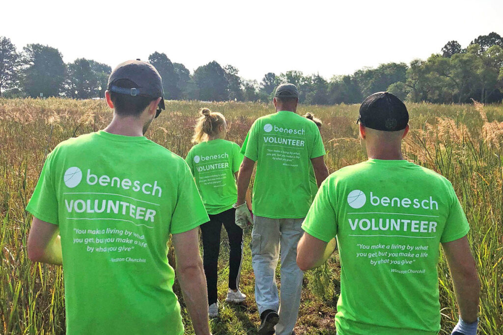 image of Benesch staff in volunteer shirts walking through a field