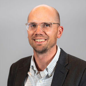 Headshot of Travis Greiman with grey background