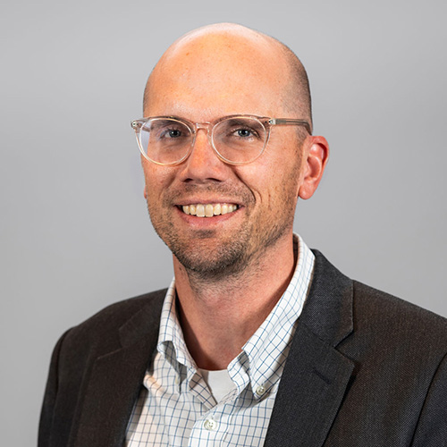 Headshot of Travis Greiman with grey background