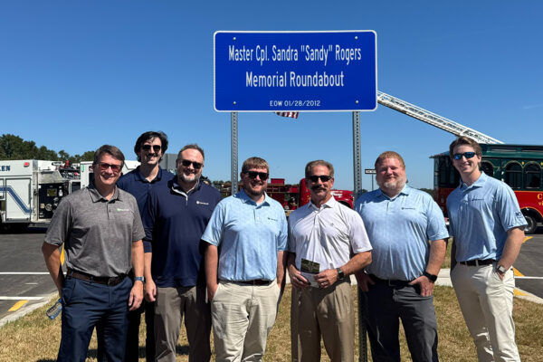Benesch stand on Tribute Parkway in front of dedication sign